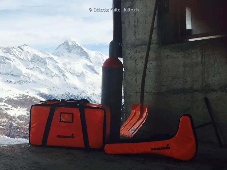 Sacs de matériel Sewerin et bouteille près d’une ouverture donnant sur les montagnes enneigées